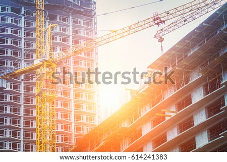 Under construction high-rise building with yellow construction crane in the sunlight Royalty-Free Stock Photo #614241383