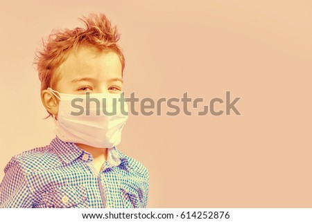 Boy with a medical mask on her face on a beige background. Toned