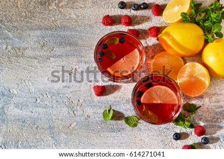 Cold berry drink with lemon and mint on a concrete background