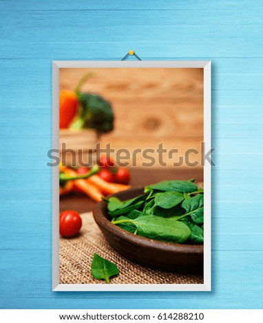 Spinach leaves in bowl. Raw fresh vegetable. Fresh natural plant leaf. Organic bio food on rustic wooden table. Photo frame on wooden rustic wall.