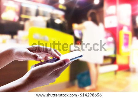 Girl use mobile phone, blur image of woman stand in front of the coffee shop as background.