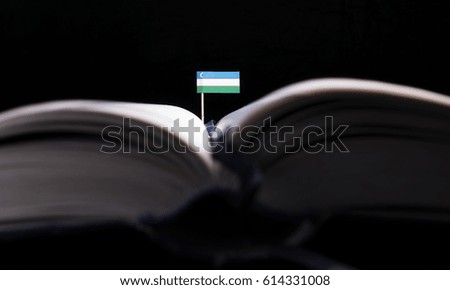 Uzbekistan flag in the middle of the book. Knowledge and education concept.