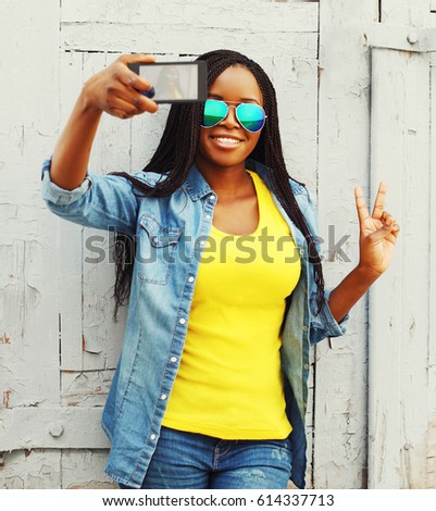 Fashion pretty young african woman taking self-portrait photo on a smartphone in the city