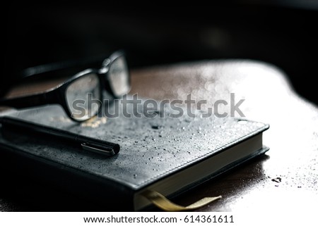 Glasses and pen are placed on the books on the  wood  table.