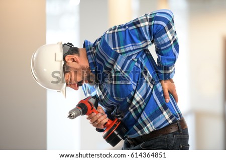 Worker getting back pain inside building Royalty-Free Stock Photo #614364851