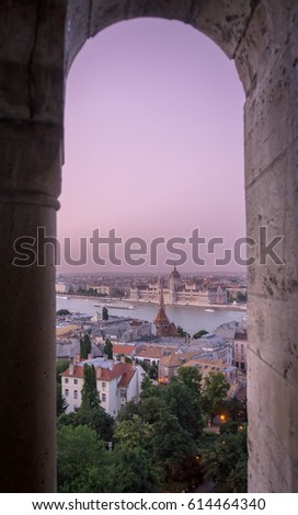 Looking through a castle window, the view of Buda in the foreground with the Hungarian Parliament building on the Pest side of Budapest in the background.