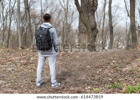 Man Traveler with backpack hiking in the spring forest, resting on the hill top. Travel and sport Lifestyle concept. Extreme vacations outdoor.