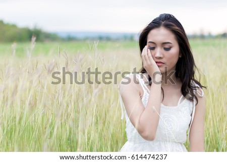Portrait of Beautiful Asian woman sitting on grass field. Feeling in wind concept 