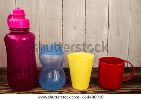 different size and colors of plastic cups on wooden background