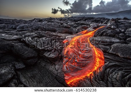 Red Orange vibrant Molten Lava flowing onto grey lavafield and glossy rocky land near hawaiian volcano with vog on background Royalty-Free Stock Photo #614530238