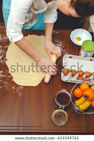 Young Woman cooking in the Kitchen, rolls the dough with a rolling pin for baking on table