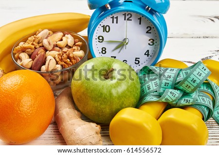 Alarm clock, dumbbells and apple. Eat and sleep rightl. Royalty-Free Stock Photo #614556572