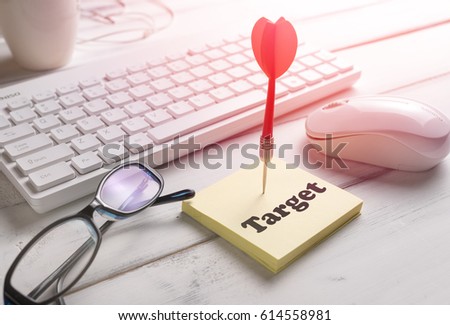 Objective or target of business concept with dart and target word on sticky note paper and keyboard mouse glasses and coffee on the wooden table, Selective focus