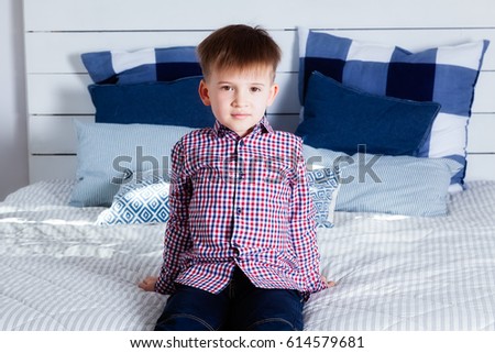The boy is sitting on the bed