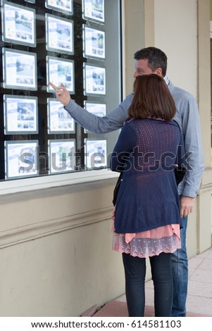 couple looks at the window of a real estate agency in the street