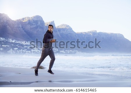 Jogging dude on beach, looking away