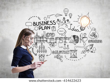 Side view of a young businesswoman in a dress standing near a concrete wall with a business plan drawning.