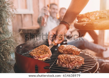 happy young friends making barbecue on porch with back light