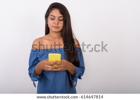 Studio shot of young Indian woman using mobile phone against white background