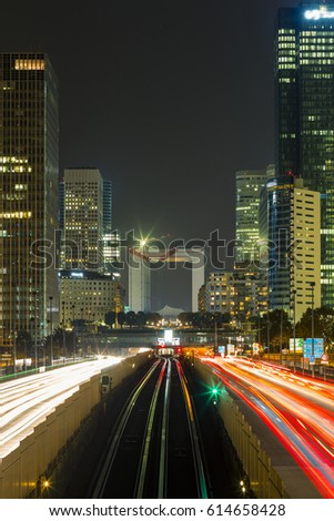 Paris night cityscape with modern buildings in business district La Defense with dynamic street traffic and car lights. Glass facade skyscrapers. Concept of economics, finances. Copy space. Toned