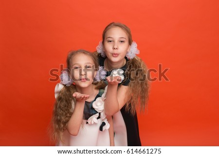 Two sisters in beautiful stylized dresses on a red background in the studio. Two blonde girls posing in studio