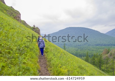 Tourists walk along a trail in the mountains