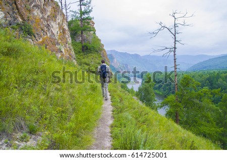 Tourists walk along a trail in the mountains