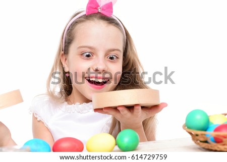 small baby girl or cute child with happy face and rabbit pink ears on blonde head around colorful easter eggs holding box isolated on white background