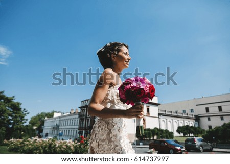 Sun shines over stunning bride walking with wedding bouquet outside