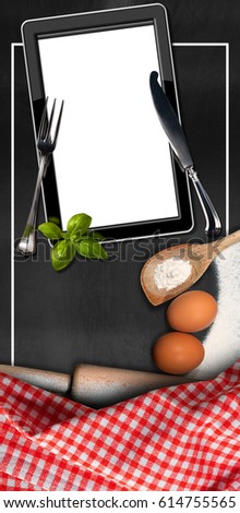 Empty tablet computer in the kitchen (empty blackboard) with utensils, flour, eggs, silver cutlery and a checkered tablecloth