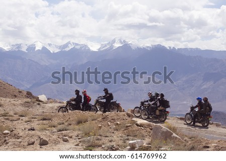 A large group of Motorcyclists on a mountainous road, cold overcast weather. Extreme sport, active lifestyle, adventure touring concept. High mountains, dirt roads.