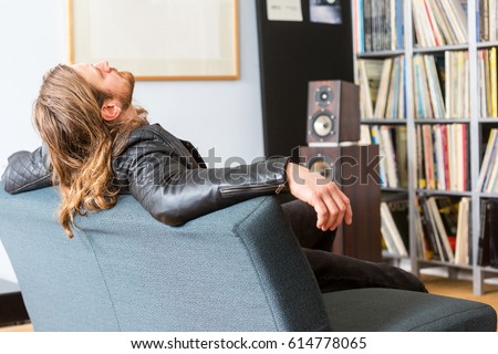 An audiophile leaning back on a couch listening to music Royalty-Free Stock Photo #614778065