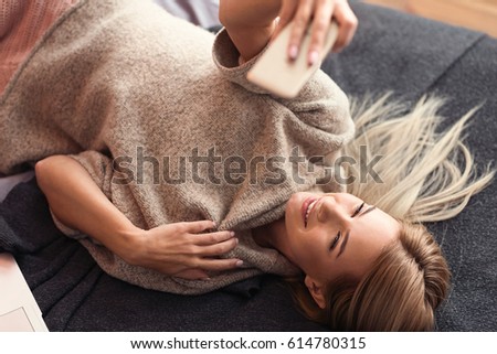 Fashionable young girl taking selfie in the bedroom