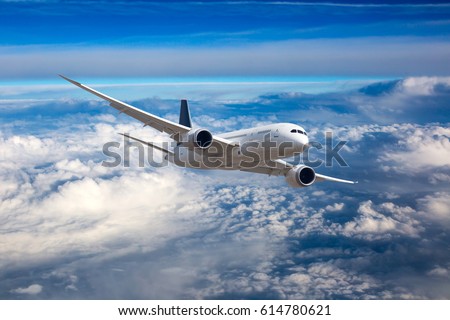 The passenger plane in flight. Aircraft flies high in the blue sky over clouds. Front view. Royalty-Free Stock Photo #614780621