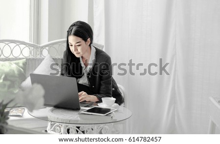 
young beautiful Business asian woman wearing  black suit sit on sofa and use laptop  in the living room