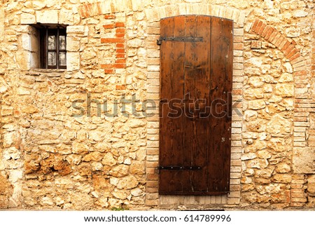 photo of Old Tuscan Wall - Brown door in a medieval stone and brick wall in the Tuscan village