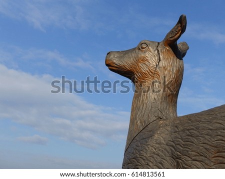 Wood carving deer head with cloudy blue sky.