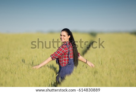 Pretty young farmer woman walking in green barley field with spread arms