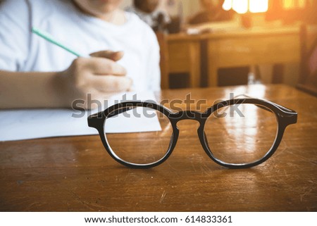 Glasses on the table in classroom and students are writing background
