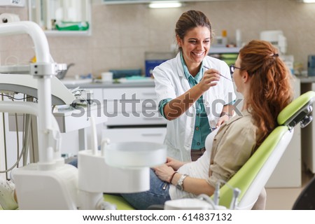 Female dentist in dental office talking with female patient and preparing for treatment. Royalty-Free Stock Photo #614837132