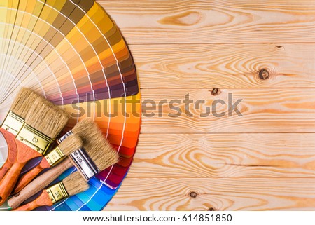 Painter and decorator work table with house project, color swatches, painting roller and paint brushes