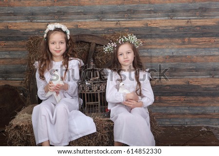 girls in garlands and white dresses holding a cage with a live pigeon and duckling
