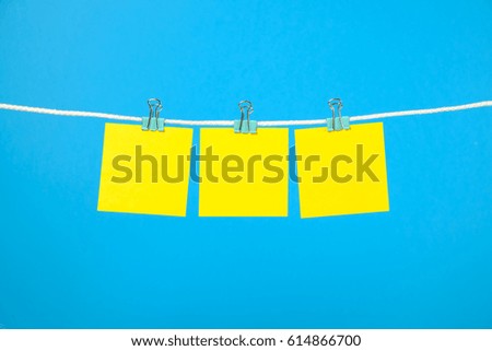 Blank yellow paper notes on clothesline over blue background