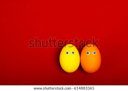 Two painted eggs with eyes. Orange and yellow eggs on a red background. You can finish their dialogue or relationship. Place for text
