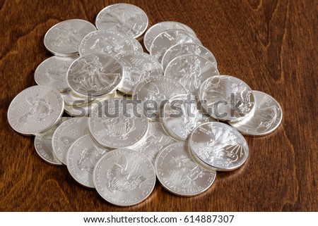 Pile of American silver dollars on a wood background
