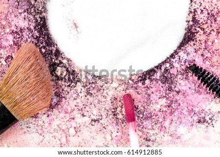 Makeup brush, lip gloss, and mascara applicator, with traces of powder and blush forming frame on white marble background. Horizontal template for makeup artist's business card, with copy space