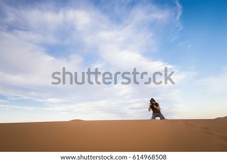 A man is taking pictures on the dunes in the Sahara Desert  at sunset - Merzouga - Morocco
