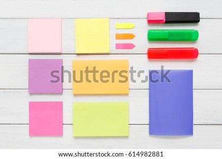Flat lay of office and business stationery supplies - colorful markers, sticky notes and memo blocks, notepad, pen on white rustic wooden board background, top view with copy space, nobody, objects