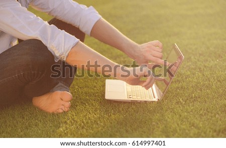 Close-up shot of handsome man's hands touching laptop computer's screen. Businessman using a laptop computer and sitting on the ground. Toned image.