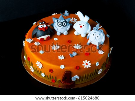 Homemade cake with mastic for children's birthday on a black background. Animation theme - smeshariki. Toned.